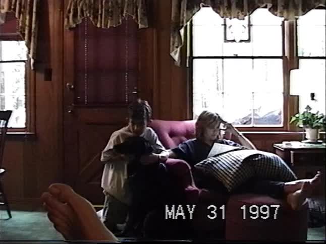 Nostalgic home video from 1997 shows two children and their dog relaxing in a cozy, wood-paneled living room