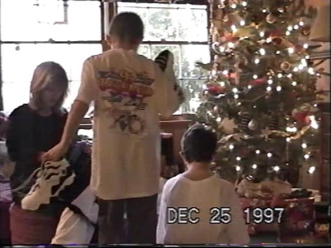 Vintage VHS footage from 1997 shows a family gathered around the Christmas tree opening presents on Christmas morning