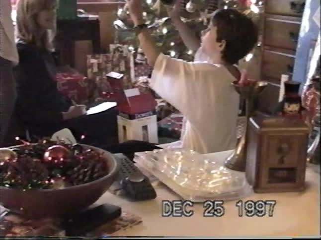 A young boy opens a new pair of shoes by the Christmas tree in this nostalgic home video from 1997