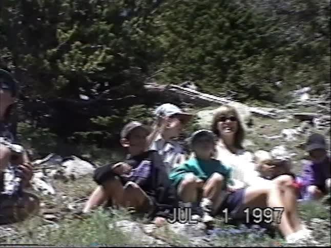 Vintage 1997 home video of a family taking a break while hiking in the mountains and pointing up at the sky