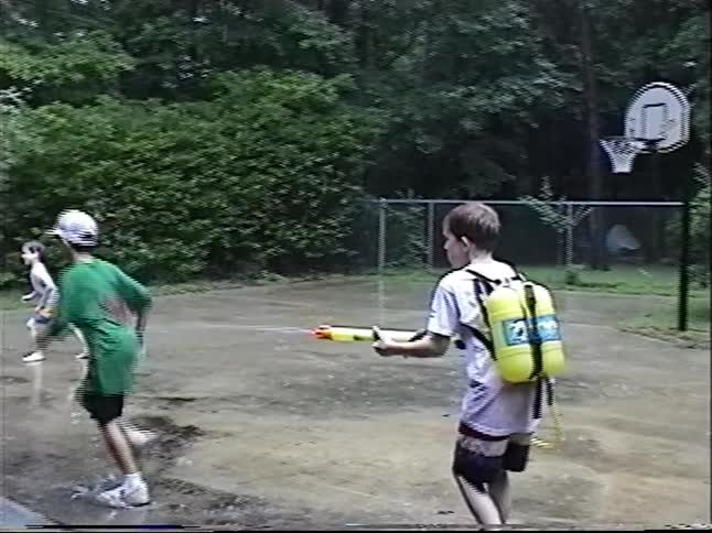 Nostalgic 1997 home video captures kids having a fun water gun fight in the rain in their backyard