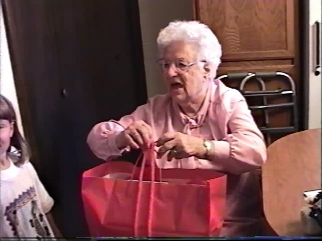A sweet elderly woman smiles as she receives a gift from her grandchildren in this authentic vintage home video from the 1990s