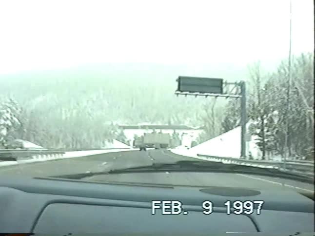 Vintage camcorder footage from 1997 captures a family's point-of-view driving on a snowy mountain highway and approaching a tunnel