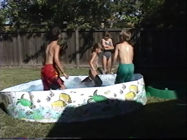 A group of kids joyfully splash and play in a small above-ground pool in their backyard on a sunny day