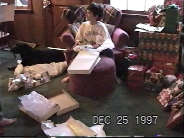 A nostalgic home video from 1997 shows two young brothers opening their presents on Christmas morning in a cozy living room