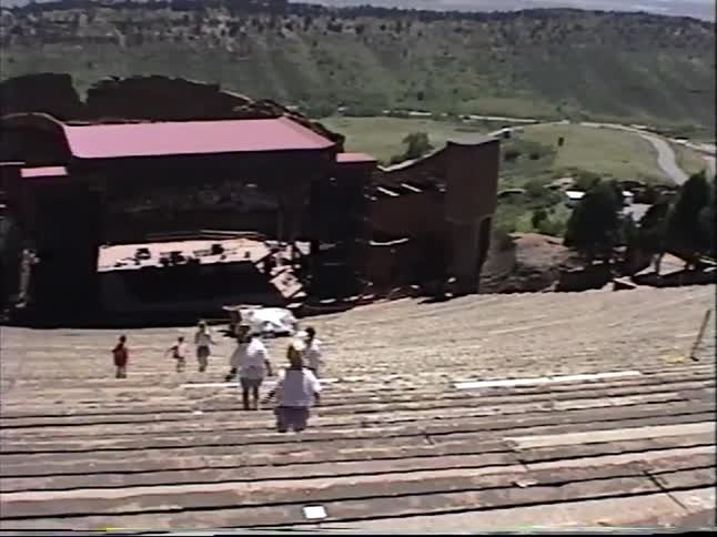 Vintage home video footage shows a family exploring the iconic Red Rocks Amphitheatre in Colorado on a sunny day