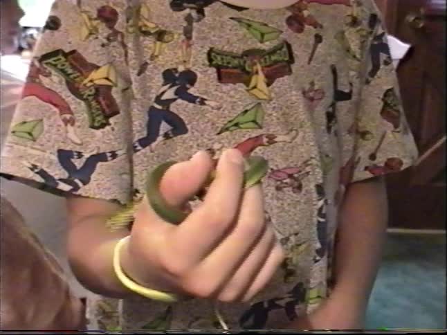 Young boy indoors gently handling a small green snake while showing it off in a home setting