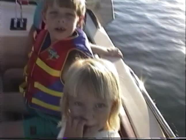 A family enjoys a sunny day boating on a lake in this nostalgic home video from the 1990s