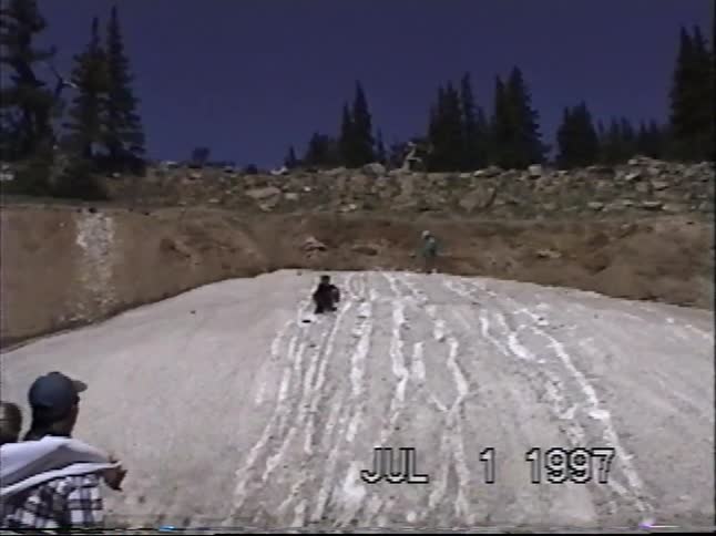 A family enjoys a fun summer day sliding down a mountain snowbank in this vintage home video from 1997