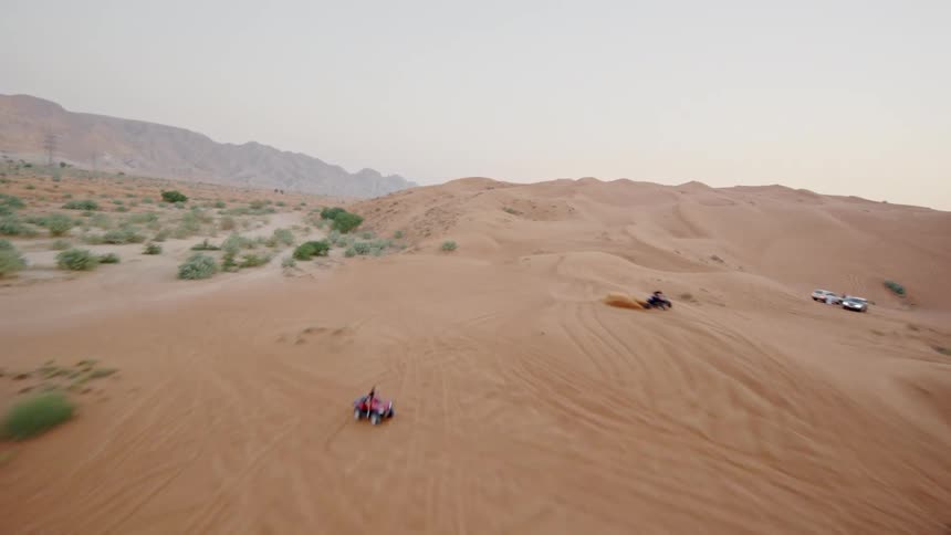 A thrilling aerial reveal of ATVs and off-road vehicles enjoying an adventure across vast desert sand dunes