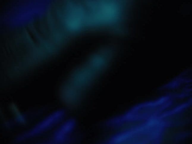 Abstract macro shot of a hand gently stroking a deep blue, textured fabric in a dark, moody setting