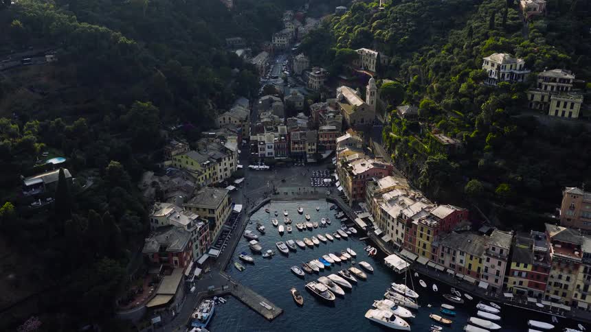 A beautiful aerial timelapse slowly descends over the picturesque harbor of Portofino, Italy, showcasing the colorful seaside village and numerous docked yachts
