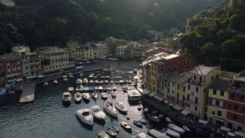 A stunning aerial shot slowly reveals the picturesque harbor of Portofino, Italy, filled with boats and lined with iconic, colorful buildings