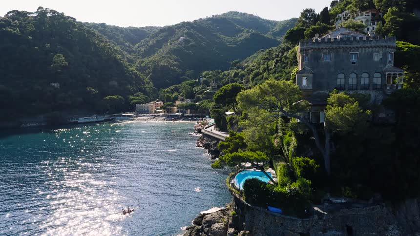 A picturesque aerial journey along the sun-kissed Italian coastline, revealing a luxurious cliffside villa and a quaint seaside village