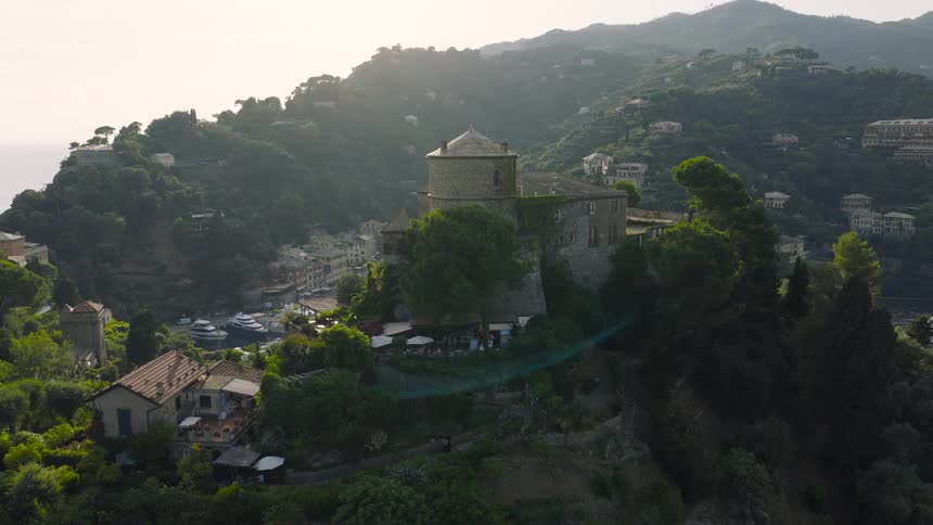 An aerial shot slowly rises above the historic Castello Brown to reveal the stunning and picturesque harbor of Portofino, Italy
