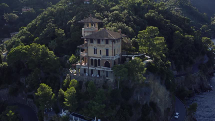 Stunning aerial view of a luxurious villa on a cliffside overlooking the ocean as the sun rises