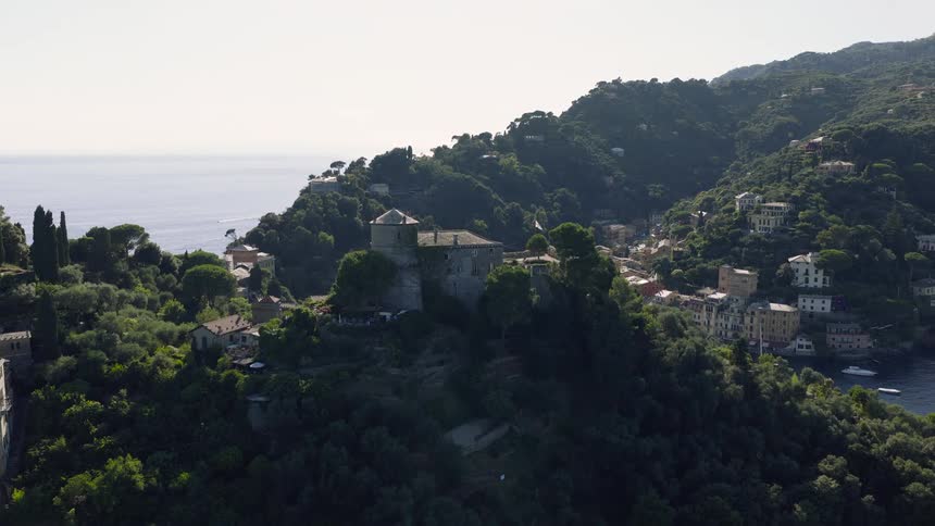 An aerial view rises over Castello Brown to reveal the picturesque harbor and town of Portofino on the sunny Italian Riviera
