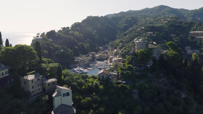 Static high-angle view of the beautiful coastal village of Portofino, Italy, with its harbor full of boats and surrounding lush green hillsides