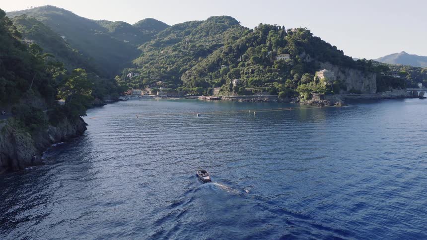 Aerial view of a boat sailing towards a picturesque cove on the Italian Riviera near Portofino on a beautiful sunny day