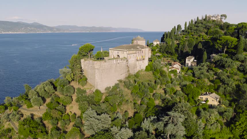 The historic Castello Brown sits majestically on a lush green hillside overlooking the calm blue waters of the Italian Riviera