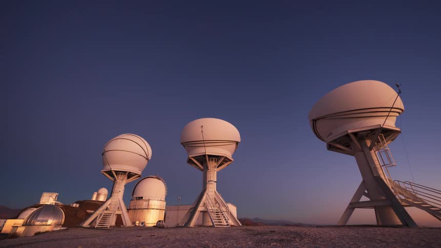 Day to night timelapse of astronomical observatory telescopes as the Milky Way rises in the starry sky