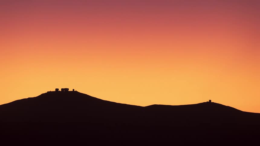 A beautiful time-lapse of the sun setting behind a silhouetted mountain observatory, transitioning from a golden hour glow to a starry night sky