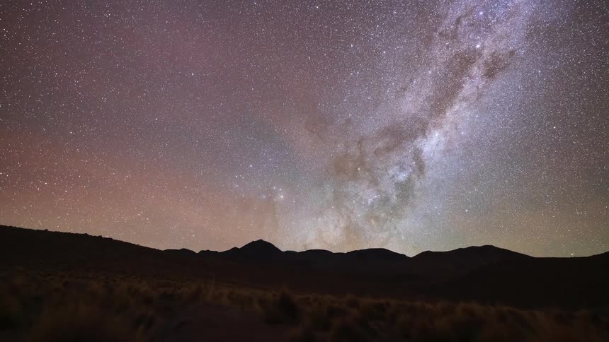 A stunning timelapse shows the Milky Way galaxy and countless stars moving across the night sky above a silhouetted mountain landscape