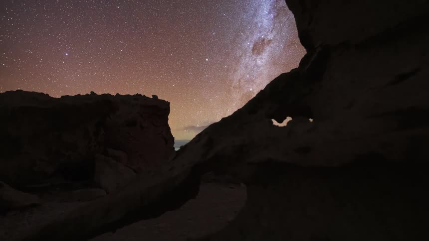 A stunning day-to-night timelapse captures the Milky Way galaxy appearing in the starry night sky over a desert rock formation