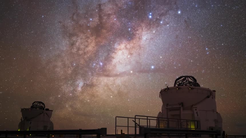 A breathtaking timelapse shows the Milky Way galaxy moving across the starry night sky above two astronomical observatories