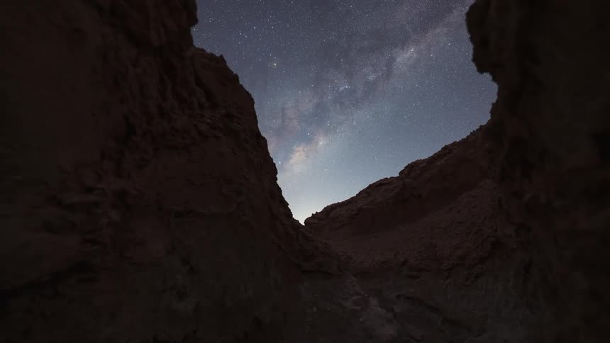 A stunning timelapse captures the Milky Way galaxy rotating across the night sky before a bright moonrise, as seen from within a desert canyon