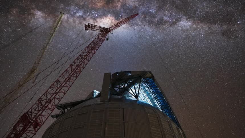 A stunning night-to-day time-lapse shows the Milky Way galaxy moving over an observatory under construction with large cranes