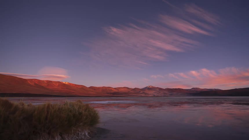 Stunning day-to-night timelapse captures a vibrant sunset transitioning to a star-filled sky over a tranquil mountain lake