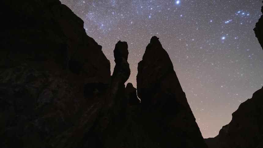 A breathtaking day-to-night time-lapse reveals the Milky Way galaxy rising over silhouetted desert rock formations