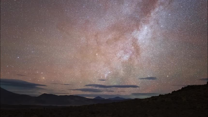 A stunning time-lapse shows the Milky Way galaxy glowing brightly as it moves across the night sky above a dark mountain landscape