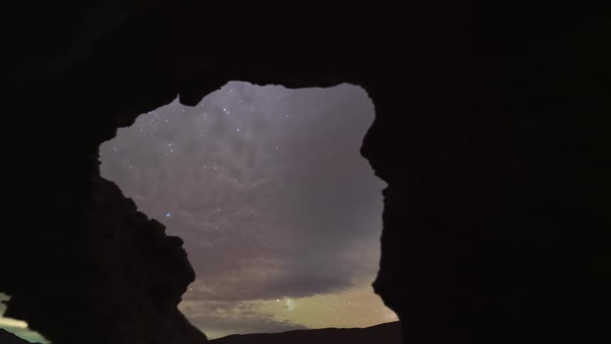 A stunning timelapse reveals the Milky Way and starry night sky through the opening of a silhouetted desert rock cave
