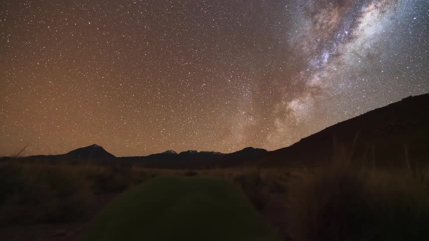 A breathtaking timelapse shows the Milky Way galaxy rotating across the starry night sky over a vast mountain landscape, culminating in a brilliant moonrise