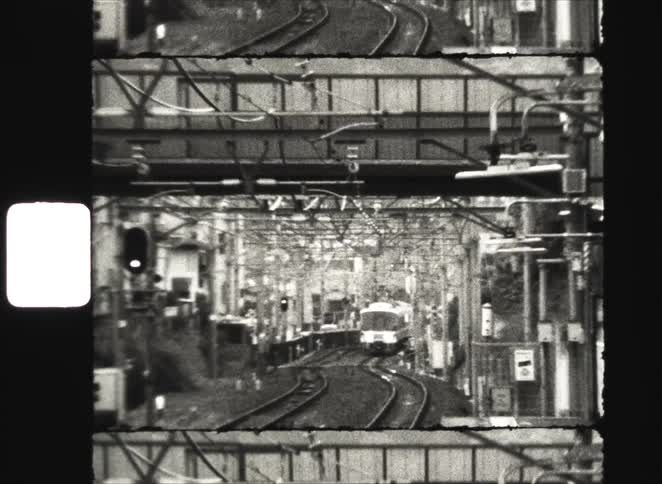 A train approaches on winding tracks in a dense urban setting in this grainy, black and white archival footage