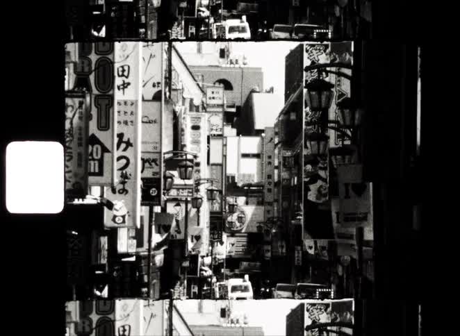 A chaotic, black and white, filmstrip collage reveals a bustling street scene in a dense Japanese city