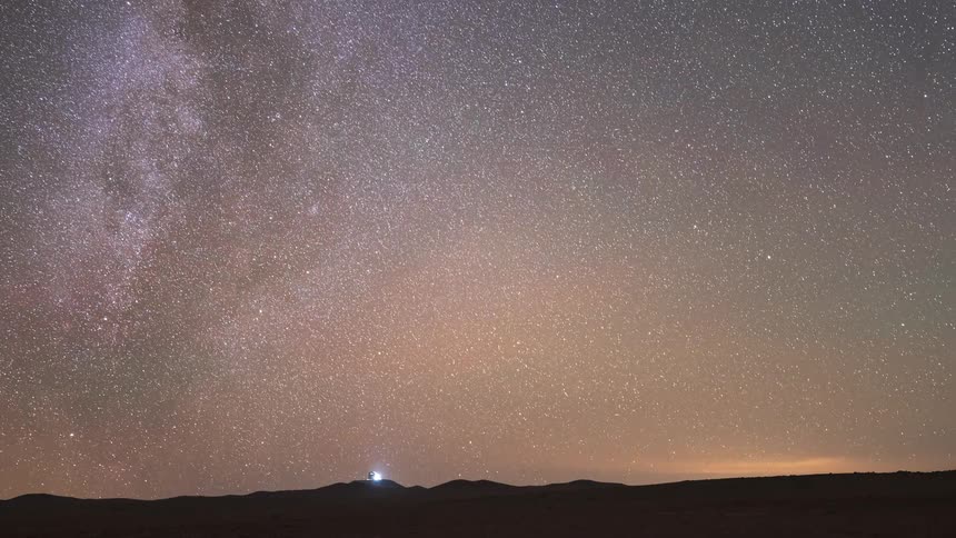 A holy grail time-lapse captures the Milky Way and starry sky transitioning from night to a brilliant sunrise over a desert landscape