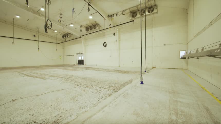 The industrial lights in a large, empty warehouse turn on and off