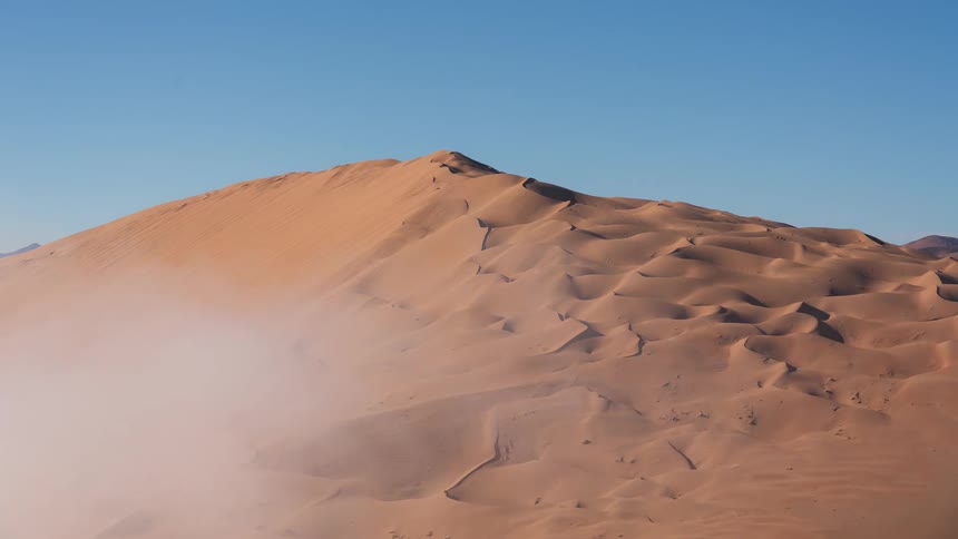 A majestic sand dune emerges from a sea of rolling morning fog that slowly dissipates