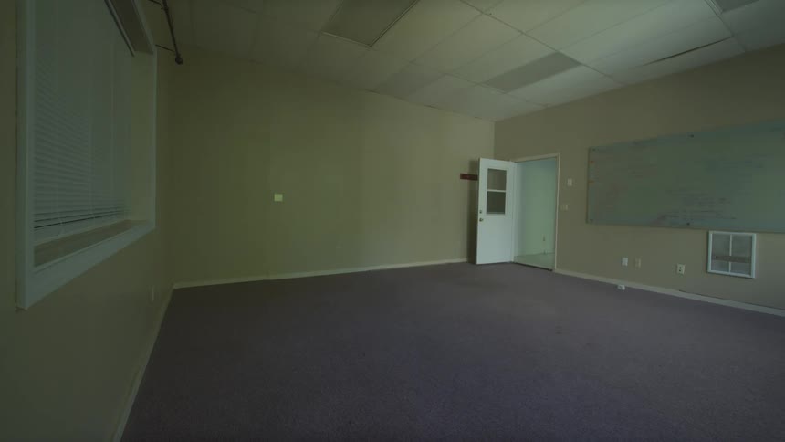 A static wide shot of a vacant and empty office space with a whiteboard on the wall