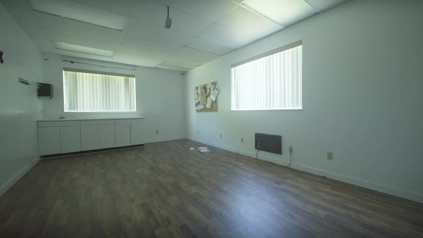 Interior wide shot of an empty, unfurnished office space with wood floors and fluorescent lighting