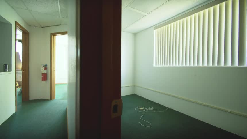A slow, unsettling pull-back shot reveals an empty office room and a deserted hallway, conveying a sense of abandonment