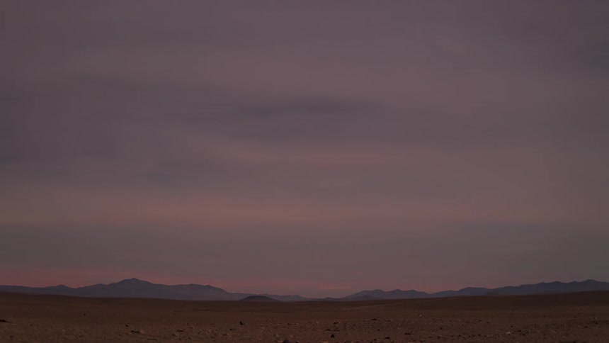 A stunning time-lapse captures the vibrant red and orange clouds of a desert sunset fading into a dark, starry night