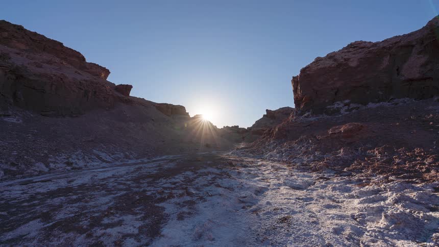 A stunning timelapse shows the sun rising over a barren, salt-covered canyon in the desert, casting long shadows that retreat as the day begins