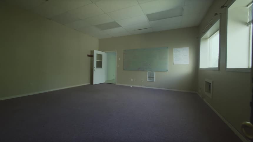 A slow-motion reveal of a large, empty office space with a whiteboard on the far wall