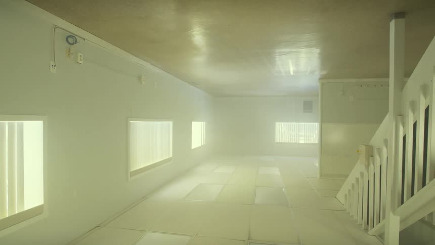 A slow, disorienting reveal of a bright, empty, and hazy room that is completely upside down