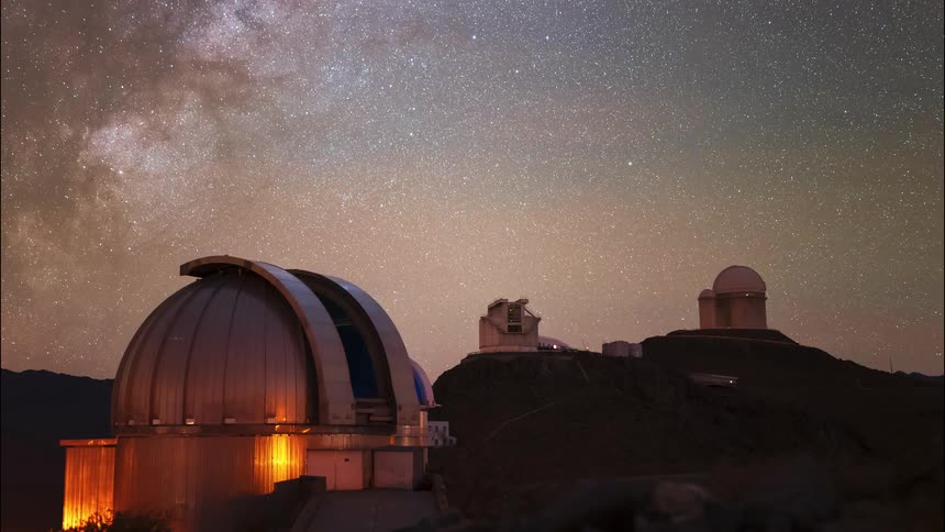 A day-to-night-to-day timelapse of an observatory on a mountain, showing the dome opening and rotating as the Milky Way and stars move across the sky before sunrise