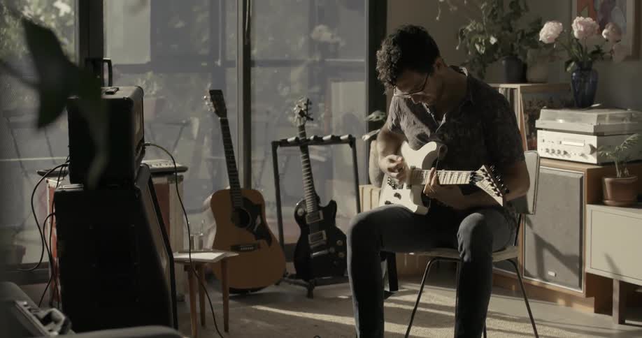 A man sits in his living room playing guitar